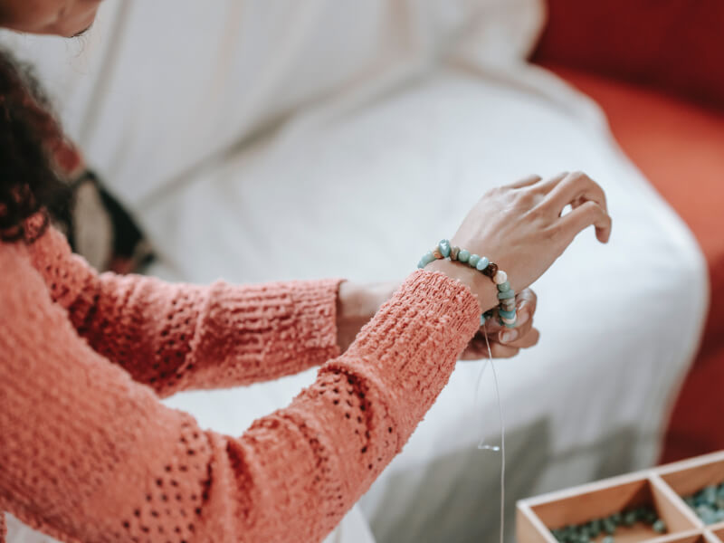 A woman tries on a beaded DIY bracelet)